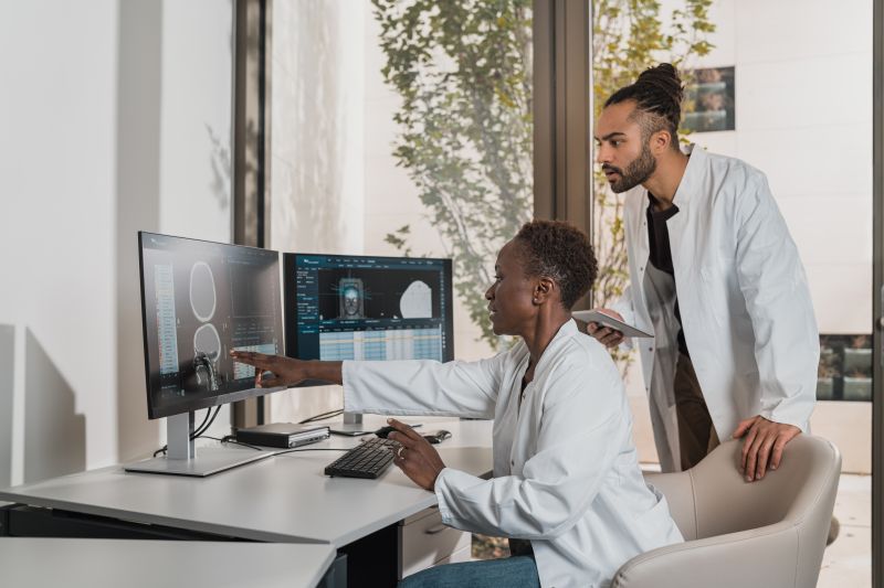 two healthcare professionals examine an image on a computer screen