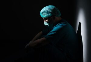a surgeon in a dark room mulling over medical errors